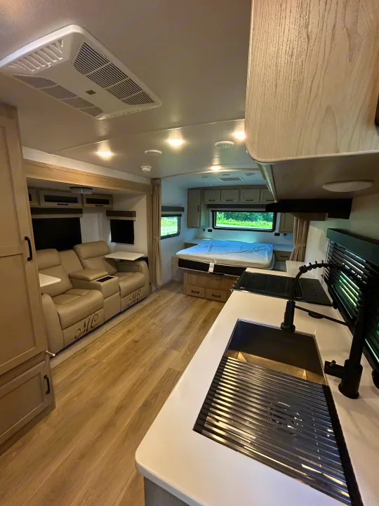 Spacious RV rental interior with living, bedroom, and kitchen areas, featuring modern light decor and wood-look flooring.. Forest River Rockwood Mini Lite 2025