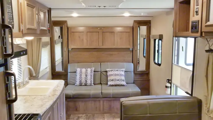 RV rental interior: kitchen, sofa with pillows, and a murphy bed wall unit create a functional living space.. Keystone RV Passport Ultra Lite 2019