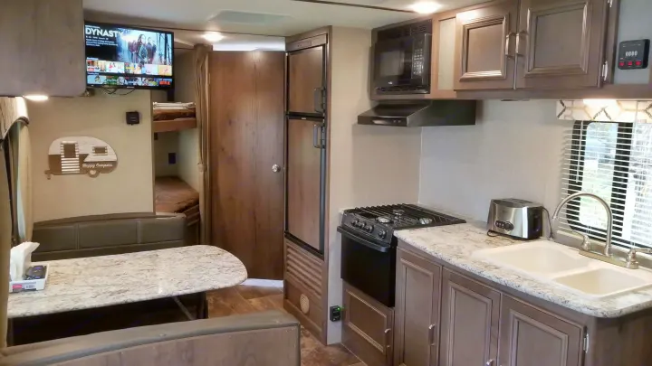 Explore this RV rental interior: kitchen with stove, sink, microwave, dining area, bunk beds, and entertainment with Netflix.. Keystone RV Passport Ultra Lite 2019