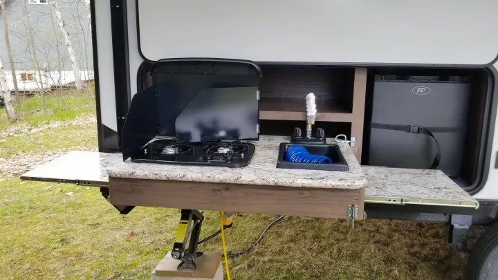 This RV rental boasts a convenient outdoor kitchen: stove, sink, mini-fridge, and pull-out countertops, perfect for camp cooking.. Keystone RV Passport Ultra Lite 2019