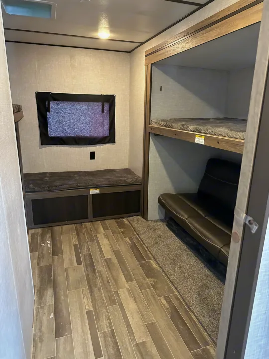 RV rental bunk area: Lower bunk with storage, window, and a set of bunk beds over a sofa. Perfect for RV trips.. Crossroads RV Zinger 2021