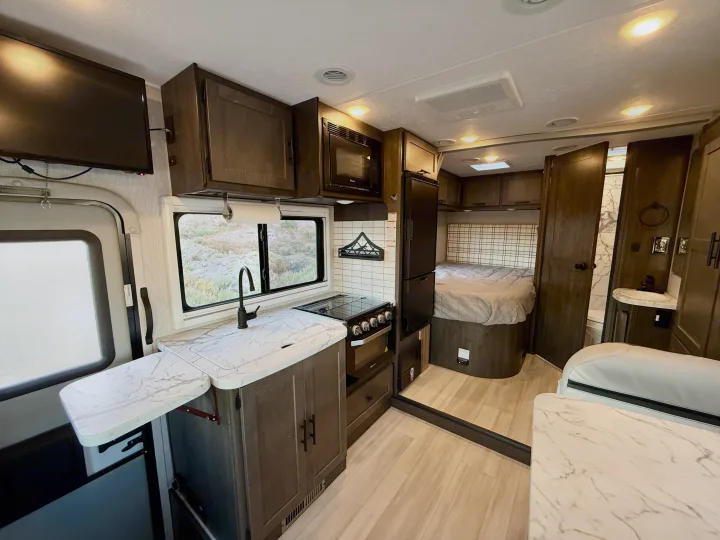 Inside this stylish rv rental: a well-equipped kitchen with marble-look counters, a comfortable bed, and compact bathroom.. Coachmen Prism Select 24CB 2022