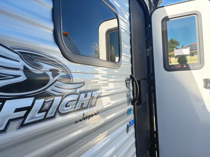 A close-up of a Jayco Flight travel trailer exterior, featuring its iconic decals and an open door, ideal for an rv rental.. Jayco 1UJBC0AJ6F7750334 2026