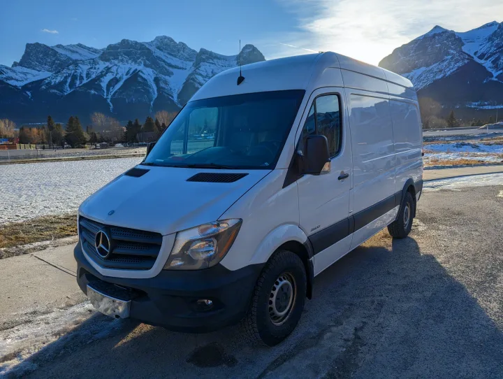 White Mercedes Sprinter RV rental van, parked with majestic snowy mountains and clear skies in the background. Ready for adventure.. Mercedes-Benz Mercedes Sprinter 2500 2015