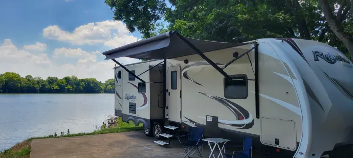 This RV rental offers a perfect lakeside camping spot. Awning extended, chairs ready for relaxation by the water.. Grand Design Reflection 2017
