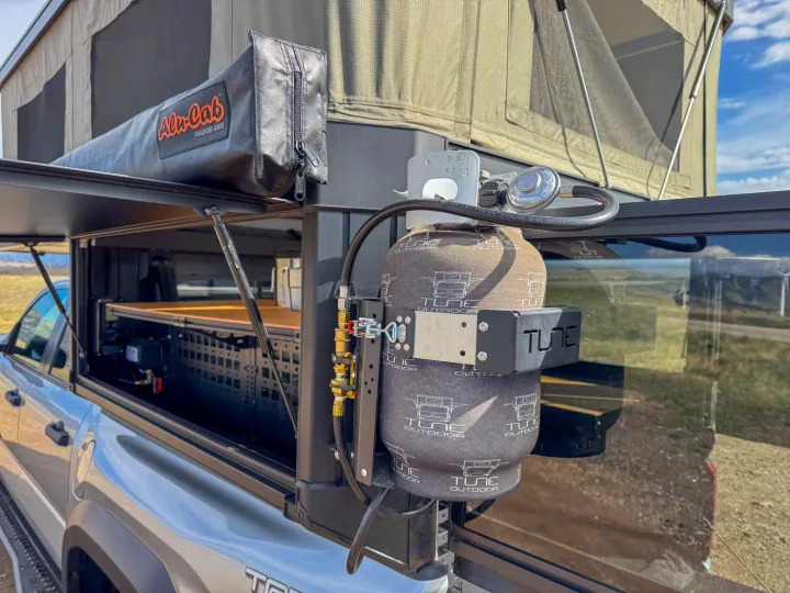 Overland truck camper with Alu-Cab awning and mounted propane tanks, ideal for an rv rental camping trip.. Toyota Tacoma 2026