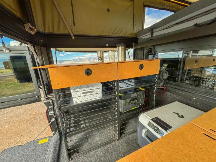 Inside an RV rental truck bed camper: Organized storage, portable power, fridge, and drawers for an overland adventure.. Toyota Tacoma 2026
