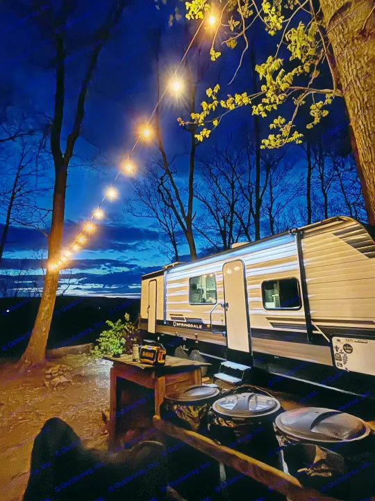 Cozy RV rental campsite at dusk. String lights illuminate a travel trailer, trees, and evening sky.. Keystone Springdale 261BHC 2026
