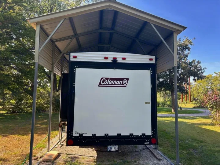 Outdoor RV rental: A Coleman toy hauler protected under a metal carport.. Coleman 270TQ 2022