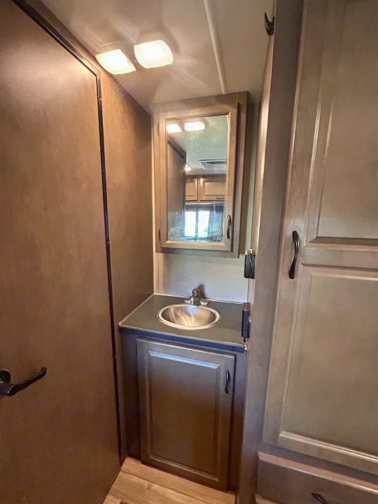 This compact RV rental bathroom features a vanity, round sink, mirrored medicine cabinet, and overhead lights.. Thor Majestic 2018