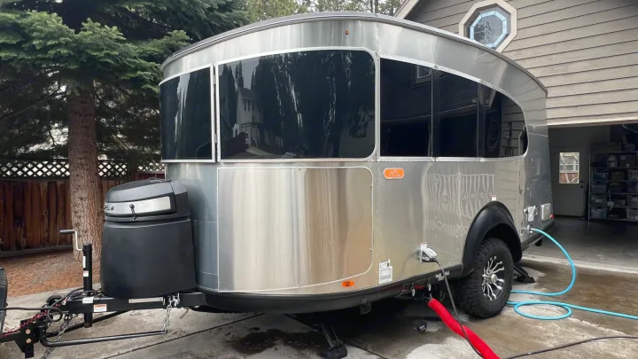 A silver Airstream Basecamp travel trailer, hooked up and ready for an RV rental journey or camping trip.. Airstream Basecamp 2022