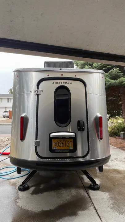 Rear of a modern silver Airstream RV rental with an Oregon plate, parked under cover with extended support legs.. Airstream Basecamp 2022