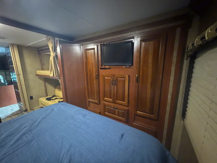 Bedroom with bed, built-in TV, storage cabinets, and bunk bed area