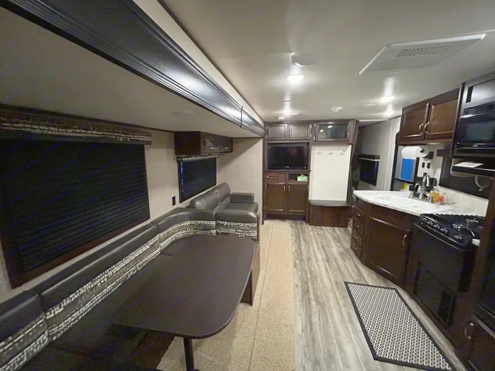Spacious RV rental interior featuring a dinette, sofa, kitchen, dark wood cabinets, and modern flooring in the living area.. Jayco Jay Flight SLX 2018