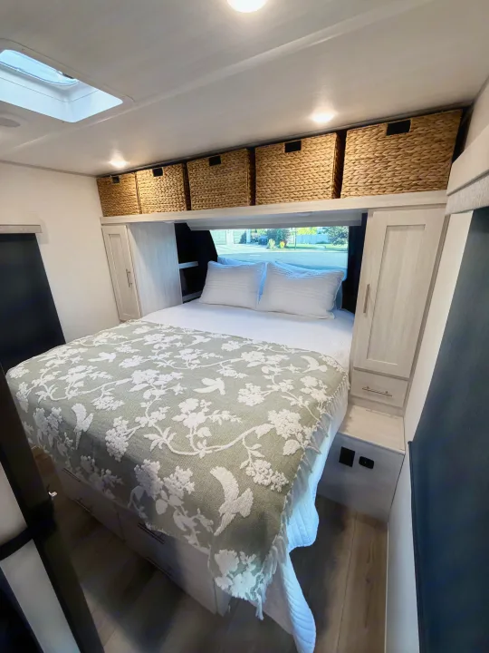 This RV rental features a cozy bedroom with skylight, stylish bed, and overhead storage for comfortable travel.. Forest River Unmapped 2026