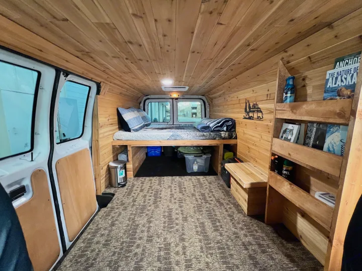 Custom wood-paneled RV rental interior. Features a comfy bed, storage, and shelves for your Alaska adventures.. Ford Econolline 250s 2013