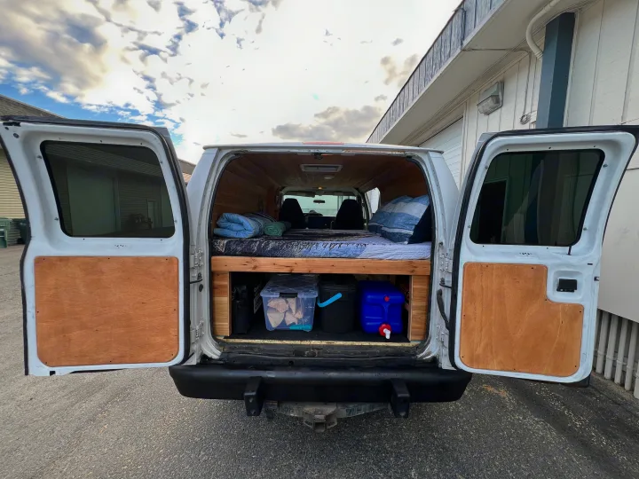 Explore the open road in this cozy camper van rv rental! Wood-paneled interior with bed, storage, and a fresh water tank.. Ford Econolline 250s 2013