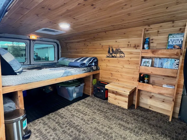 Cozy wood-paneled camper van interior with a bed, storage, and Jackery power station, ideal for an RV rental adventure.. Ford Econolline 250s 2013