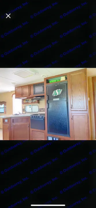 This rv rental features a compact kitchen with wood cabinets, microwave, stove, sink, and a Saskatchewan Roughriders fridge.. Forest River Tracer Executive 2010