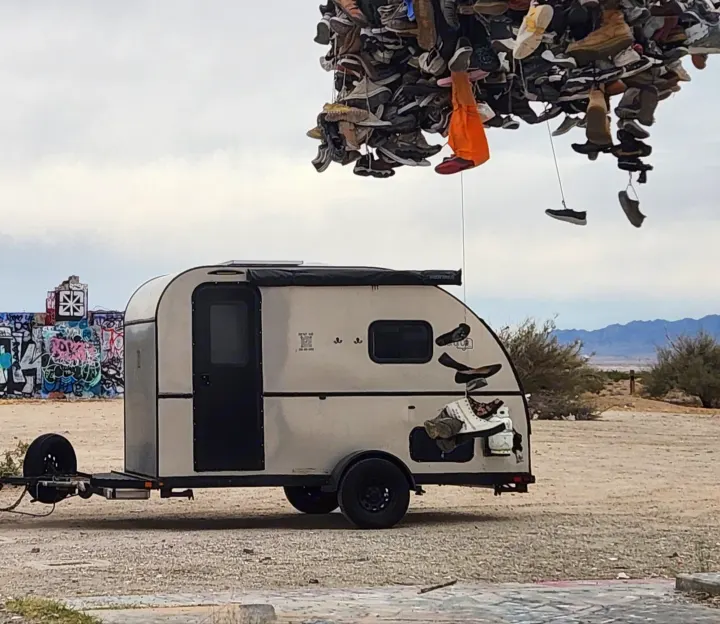Unique RV rental camper parked near a shoe tree art installation and graffiti walls in a desert. Adventure awaits!. Bend Teardrop Tall Boy 2023