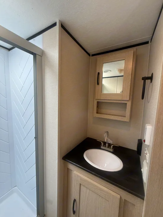 RV rental: Clean, compact bathroom with a modern shower, vanity sink, and mirrored medicine cabinet.. Coachmen Apex 2021