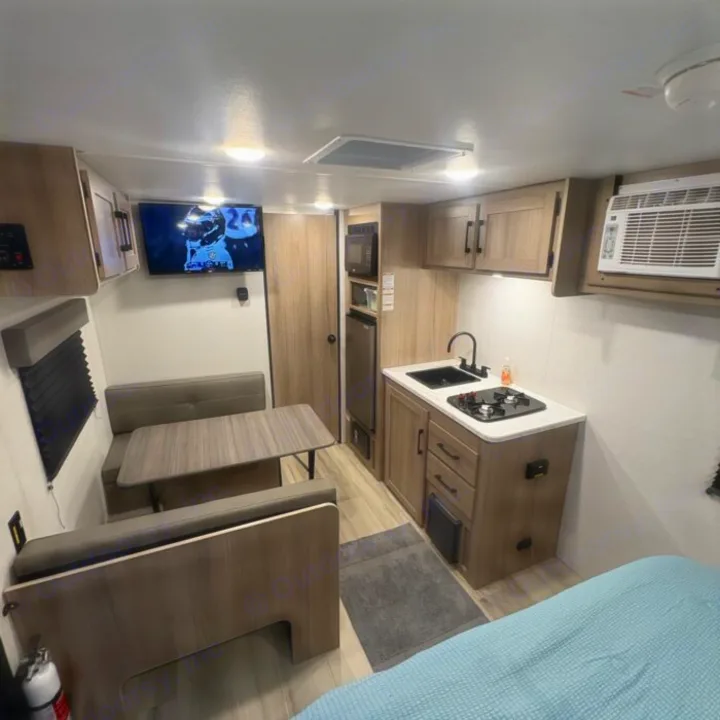 Compact and modern rv rental interior featuring kitchen, dining, TV, and bed. Perfect for your next adventure!. Keystone RV Coleman 2025