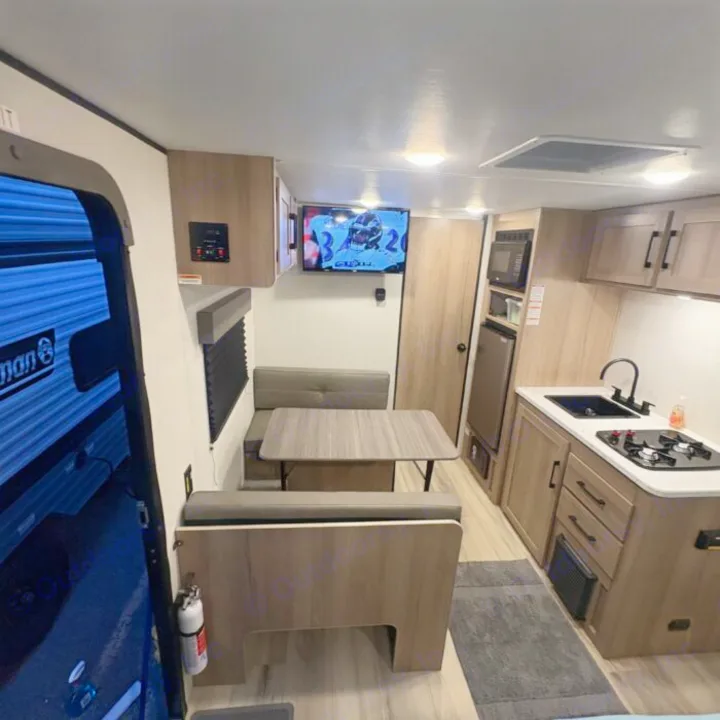 Cozy RV rental interior: a modern kitchen, dinette, and TV create a comfortable, compact living space for travel.. Keystone RV Coleman 2025