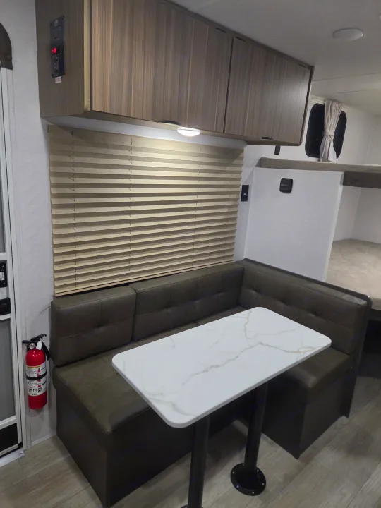 This rv rental features a cozy dinette with U-shaped seating, a white marble-look table, and overhead cabinets.. Forest River Salem 2026