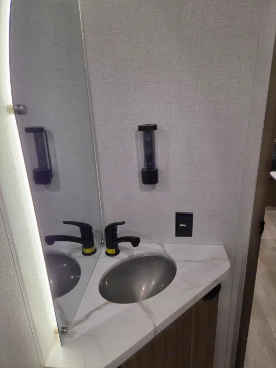 RV rental bathroom: Sleek corner sink, black faucet, mirror with LED light, outlet, and wall dispenser.. Forest River Salem 2026