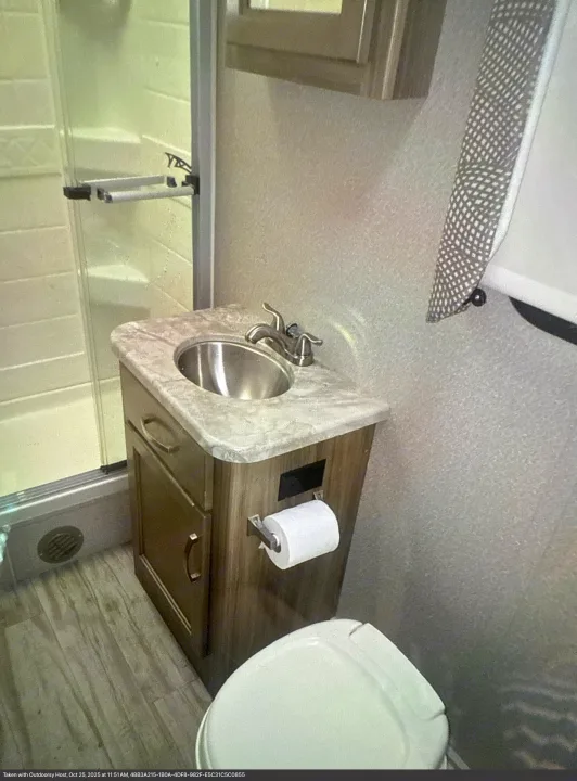 This rv rental bathroom features a compact sink, vanity with toilet paper, partial toilet, and a clear glass shower stall.. Entegra Coach Vision 2019