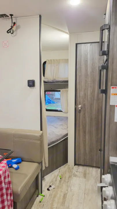 Inside an RV rental featuring bunk beds, a dining booth, thermostat, and wood-look flooring. Ready for your next adventure!. Highland Ridge RV Open Range 2020