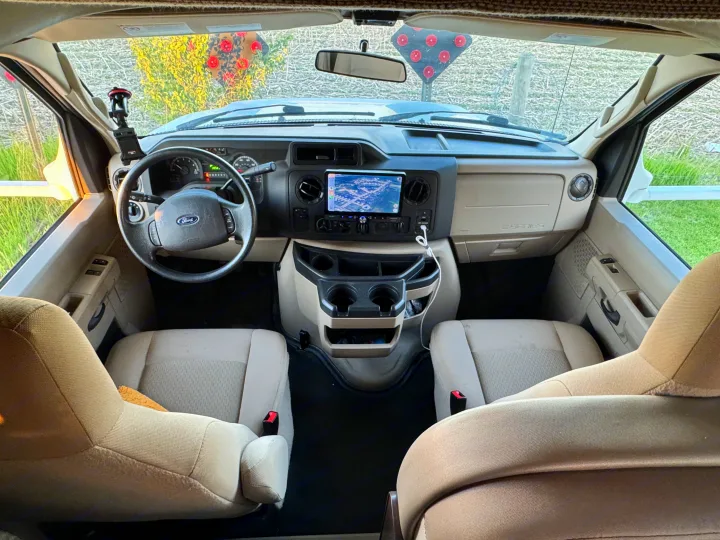 This RV rental's spacious front cabin features a detailed dashboard, navigation screen, steering wheel, and comfortable seats for travel.. Thor Freedom Elite 2017