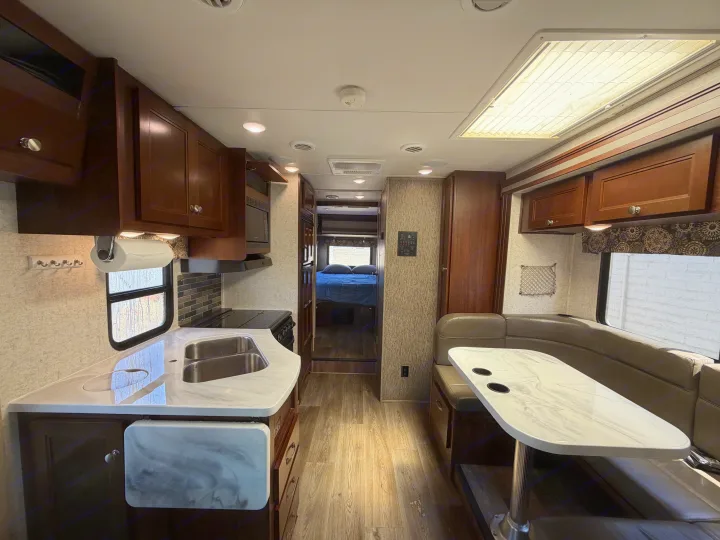Spacious RV rental interior with a fully-equipped kitchen, dining booth, and view towards the bedroom. Perfect for travel.. Forest River Sunseeker 2017
