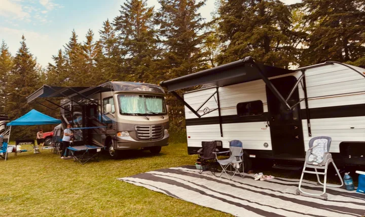 Two RVs, a motorhome and a travel trailer, parked on grass at a sunny campsite, perfect for an RV rental adventure.. Cruiser RV Avenir 2024
