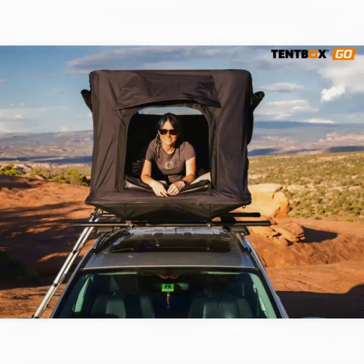 Smiling from a car rooftop tent, a great camping alternative to an RV rental for your desert travel adventure.. TENTBOX GO 2026