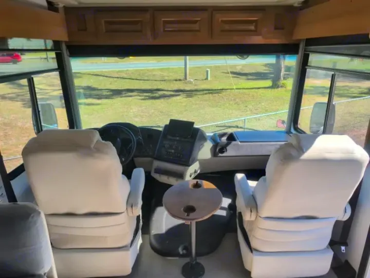 Inside an RV rental: View of the driver's and passenger's cockpit seats, dashboard, and front window to the road.. Forest River GEORGETOWN 36D7 2024
