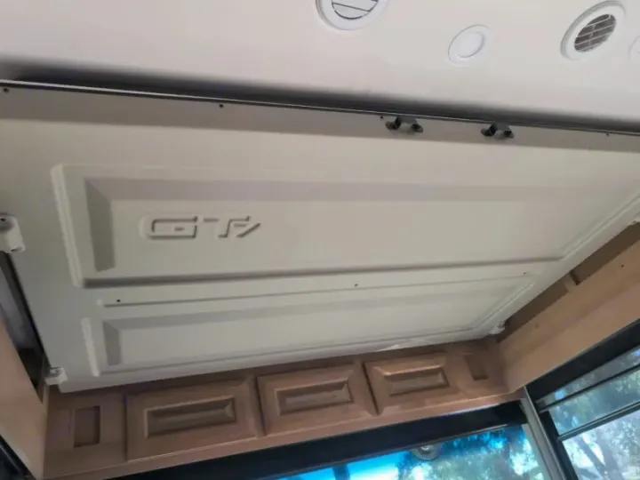 RV rental interior: Overhead retractable bed with 'GT' emblem, above wooden cabinets. Ceiling vents visible.. Forest River GEORGETOWN 36D7 2024