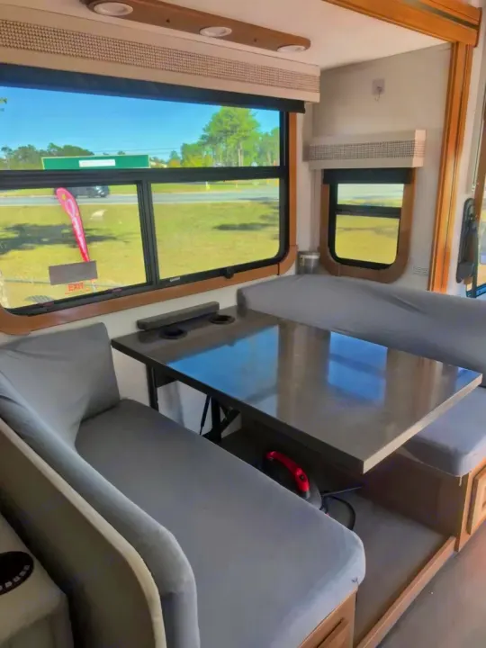 Modern RV rental dinette featuring grey bench seating, a practical table, and large windows with outdoor views.. Forest River GEORGETOWN 36D7 2024