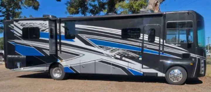 Modern black, blue, and gray Class A RV rental with dynamic graphic stripes, parked outdoors, ready for your road trip adventure.. Forest River GEORGETOWN 36D7 2024