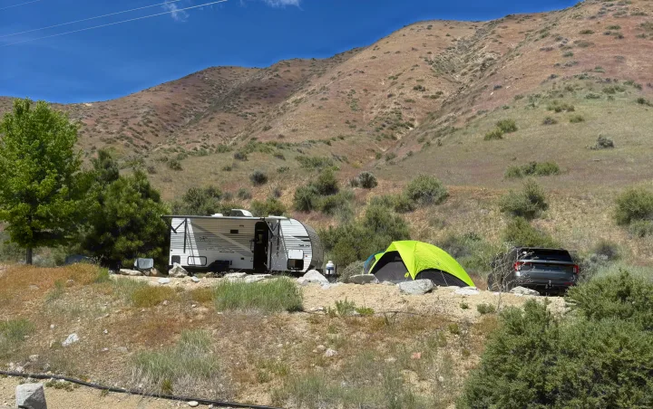 RV rental, bright green tent, and SUV at a sunny mountain campsite. Ideal for outdoor adventures.. Jayco Jay Flight SLX Baja Edition 2025