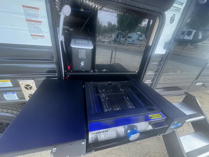 This rv rental shows an outdoor kitchen with a grill, ice maker, and shower, perfect for camping convenience.. Forest River 26KF 2026