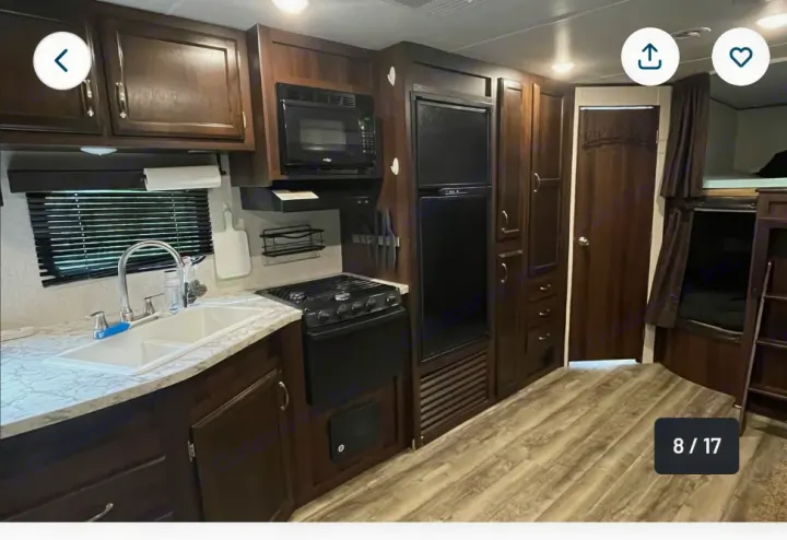This rv rental features a modern kitchen with dark cabinets, appliances, and cozy bunk beds, ideal for travel.. Jayco Jay Flight SLX 2018