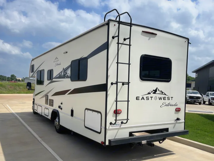 This East West Entrada RV rental, a white motorhome with a ladder, is parked for your next road trip adventure.. Entrada Entrada Motorhome 2022