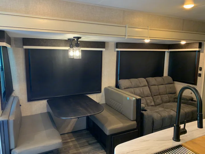 Spacious RV rental interior featuring a modern dinette, plush sofa with cup holders, and a glimpse of the kitchen. Ideal for travel.. Jayco Eagle HT 2022