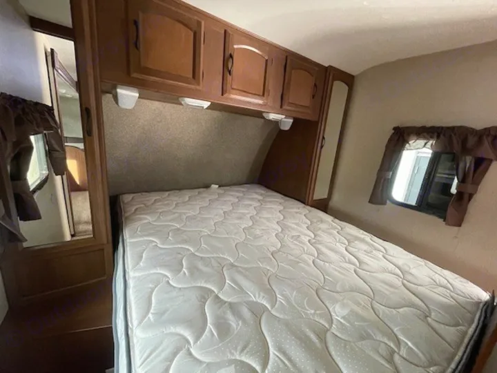 RV rental bedroom: cozy space with a comfy bed, overhead storage, & window with curtains, ideal for travel.. Coachmen Freedom Express 2015