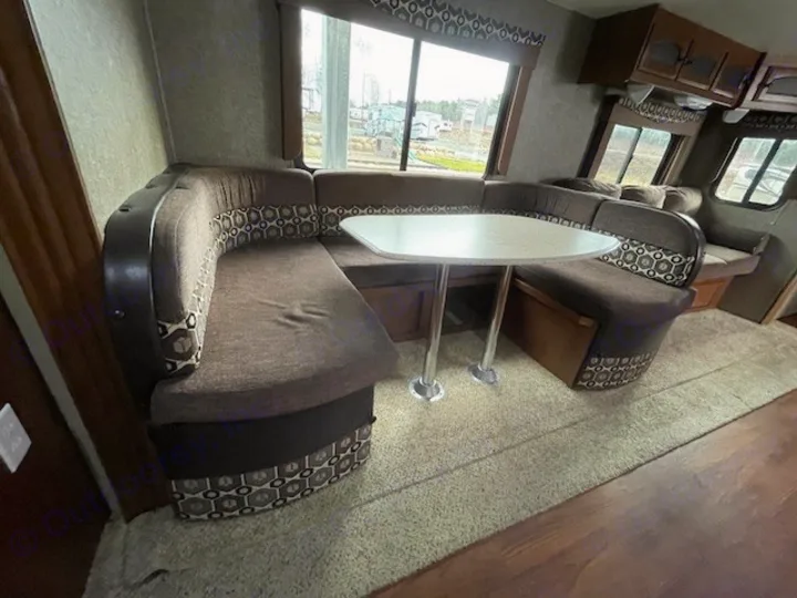 Inside this RV rental, find a spacious U-shaped dinette booth with a table, ideal for dining or relaxing.. Coachmen Freedom Express 2015