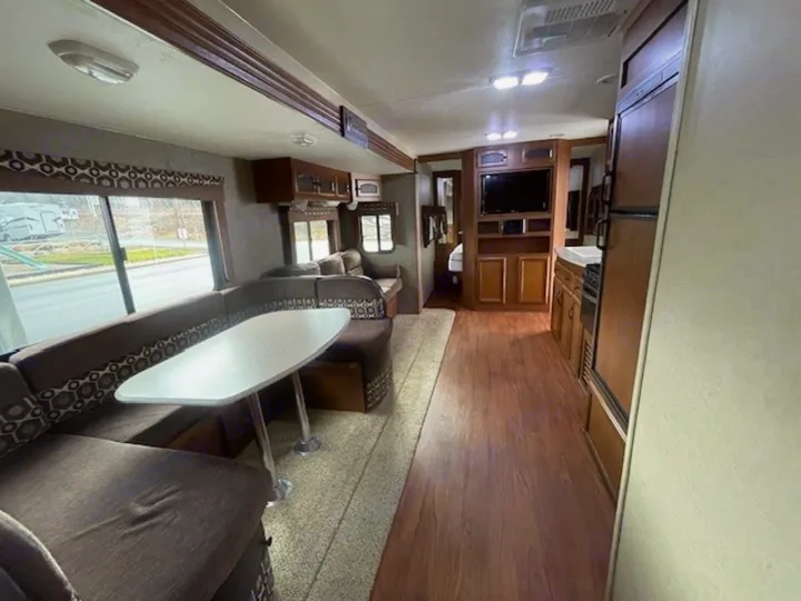 Spacious RV rental interior featuring a large dinette, kitchen, entertainment center, and wood floors. Ideal for your next adventure.. Coachmen Freedom Express 2015