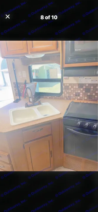 Functional rv rental kitchen with a double sink, Magic Chef microwave, stove, and wood cabinets, ready for your road trip meals.. Puma Puma 2011