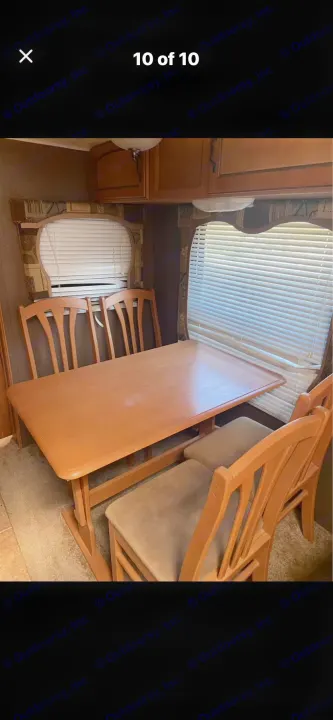 RV rental interior: Cozy dining area with a wooden table and four upholstered chairs, flanked by windows with blinds and overhead cabinets.. Puma Puma 2011