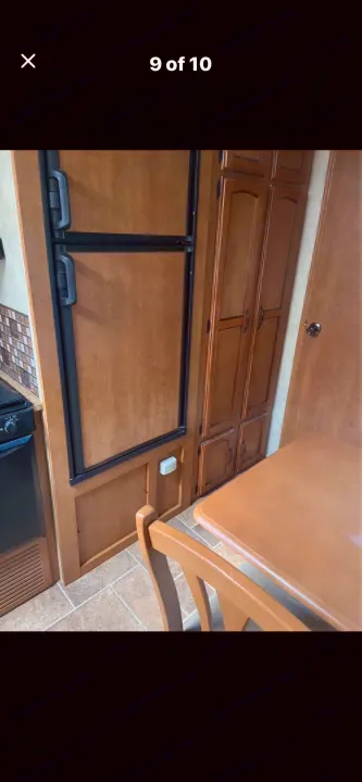 RV rental kitchen with a built-in refrigerator, pantry, stove, and dining table/chair, all in warm wood tones.. Puma Puma 2011
